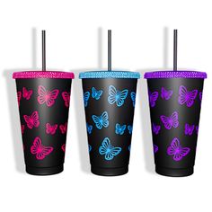 three different colored tumblers with butterfly designs on the sides and one has a straw in it