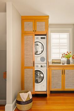 a washer and dryer in a room with wood floors, cabinets, and drawers