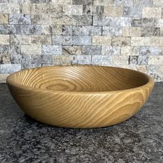 a wooden bowl sitting on top of a counter next to a tiled backsplash