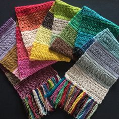 six crocheted scarves with fringes in different colors on a black background