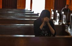 a woman covering her face while sitting in pews