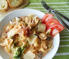 a white bowl filled with pasta and veggies on top of a green table cloth