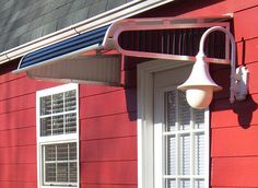 a red house with white shutters and a lamp