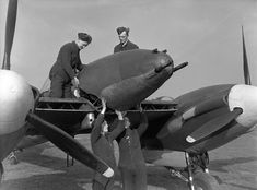 two men standing next to an old airplane