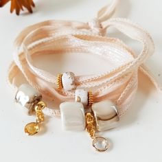 Casual Bracelet in beige and ecru tones, bohemian and romantic style. This boho bracelet is inspired by the streets of Paris. It is a very modern and youthful bracelet but it has an elegant and cool touch. It is made with a 65 cm long cotton ribbon where several Greek porcelain beads in beige-gold tones have been inserted and combined with several different types of golden charms. This wraparound bracelet wraps around your wrist three times and ties at the back. It can also be used as a necklace Bohemian Beige Bracelet For Festivals, Bohemian White Friendship Bracelets With Adjustable Length, White Bohemian Friendship Bracelets With Adjustable Length, Bohemian Wrap Bracelet As A Gift, Elegant Adjustable Bracelets For Beach, Elegant Adjustable Beach Bracelets, Elegant Beaded Wrap Bracelet As Gift, Handmade Elegant Beach Bracelets, Elegant Beige Beach Bracelet