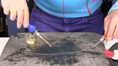 a woman is using scissors to cut up something on a piece of metal that has been placed on top of a table