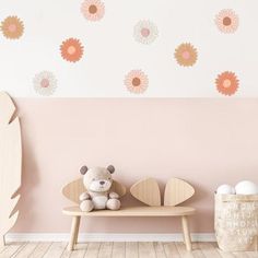 a teddy bear sitting on a bench in front of a wall with flower decals