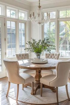 a dining room table and chairs with chandelier in the background, surrounded by windows