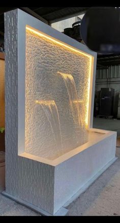 an outdoor fountain that is lit up and has water running down it's sides