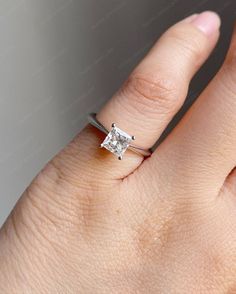 a woman's hand with a diamond ring on top of her finger, showing the center stone