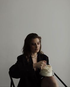 a woman sitting down with a cake in her hand