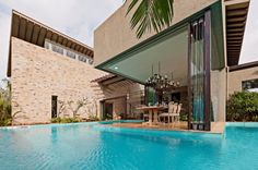 an outdoor pool next to a house with a table and chairs in the middle of it