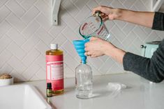 a person pouring water into a bottle on top of a counter