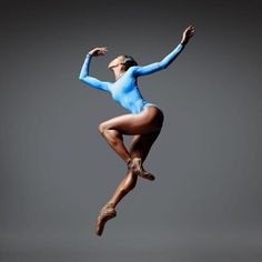 a woman in a blue leotard is jumping