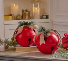 two red tomatoes with faces painted on them sitting on a table next to christmas decorations