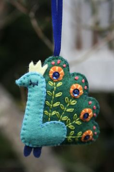 an ornament shaped like a giraffe hanging from a blue ribbon with flowers on it