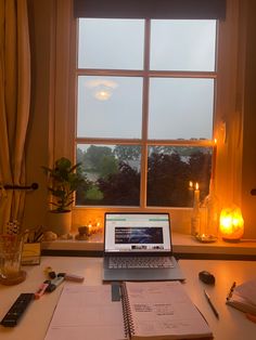 an open laptop computer sitting on top of a desk next to a window sill