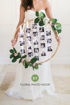 a woman in a white dress holding a hoop with photos and greenery on it