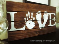 a wooden sign with the word love painted on it and hand prints in white ink