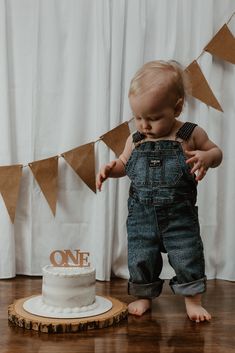 a baby standing in front of a cake