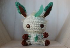 a crocheted stuffed animal sitting on top of a wooden shelf next to a white wall