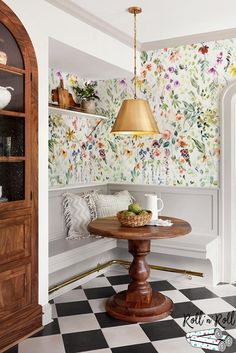 a dining room with floral wallpaper and a table in the corner, next to a doorway