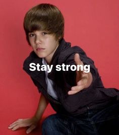 a young man sitting on the ground with his hand up to say stay strong,