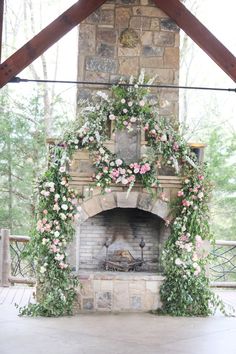 an outdoor fireplace decorated with flowers and greenery