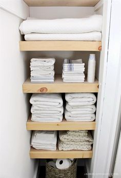 towels are stacked on wooden shelves in the closet