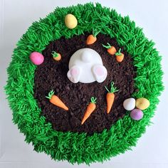 a cake made to look like a bunny with carrots and grass around it on a white surface