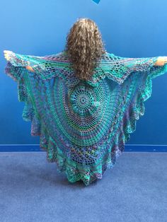 a woman wearing a crocheted shawl and holding her arms behind her back