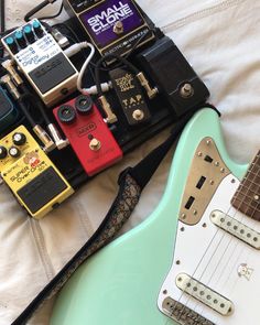 an electric guitar and other musical instruments on a bed