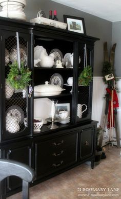 a black china cabinet with white dishes on it