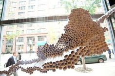 there is a sculpture made out of tubes on the window sill in front of a building