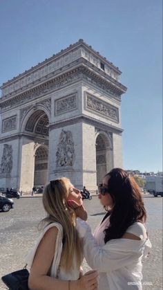 two women standing in front of the arc de trioe