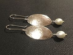 Classical Timeless and Elegant, Silver and Pearl Dangles will flatter for years if not a lifetime. A perfect gift for yourself or that Special Someone! These lovely earring are made from Argentium Sterling Silver and Oval Pearls to compliment.  They will hang 2.5 inches from your piercing.  Hammered to catch the Light and provide a Modern Edge to a Minimalist Design.   All my pieces are personally made by me specially for you in my studio.So I am thinking of posting this in a picture. CANADA - GST/HST included in prices.  Provincial tax, where applicable, is added at checkout. UNITED STATES - taxes included at checkout. Returns are not accepted on worn items.  Items must be received unworn and in the condition they were shipped to receive a refund.  For health and safety reasons no worn ea Classic Hammered Earrings For Anniversary, Formal Oval Hammered Jewelry, White Gold Oval Pearl Drop Earrings, Elegant Handmade Oval Pearl Earrings, Oval Hypoallergenic Jewelry For Anniversary, Hypoallergenic Oval Jewelry For Anniversary, Oval Hammered Jewelry For Wedding, Oval Hammered Wedding Jewelry, Classic Oval Pearl Earrings With Ear Wire