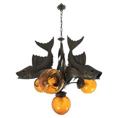 a chandelier with three fish hanging from it's sides and an orange glass ball on the bottom