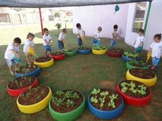 children are playing in the yard with colorful plastic barrels filled with dirt and plants that have been planted into them