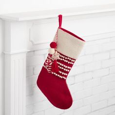 a red and white christmas stocking hanging from a mantel