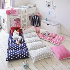 two children are sleeping in their beds on the floor next to each other, with pink and blue pillows