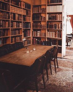 an old library with many bookshelves full of books and chairs around a wooden table