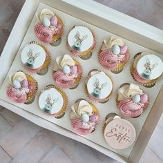 cupcakes decorated with pink and white frosting in a box