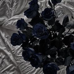 a bouquet of blue roses sitting on top of a white sheeted bed cover covered in sheets