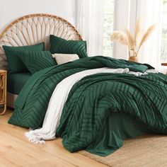 a bed with green comforters and pillows in a room next to a wicker headboard