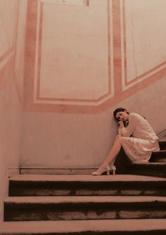 a woman is sitting on the stairs talking on her cell phone