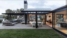 an outdoor living room and dining area with glass walls