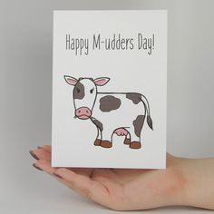 a hand holding a card that says happy m - udders day with a cow