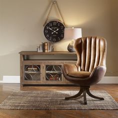 a brown chair sitting on top of a rug next to a table with a clock