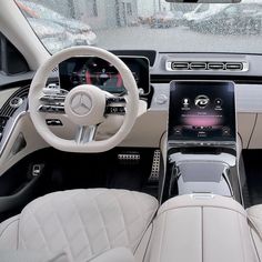 the interior of a modern car with white leather seats and steering wheel, including an electronic display