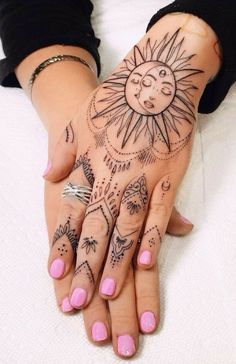 a woman's hand with tattoos on it, and the sun in the middle